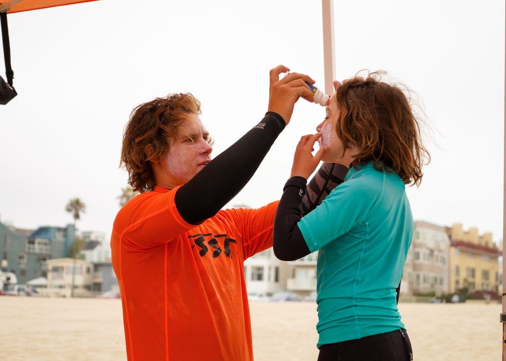 A camp counselor helping apply sunscreen to a camper in Venice Beach.